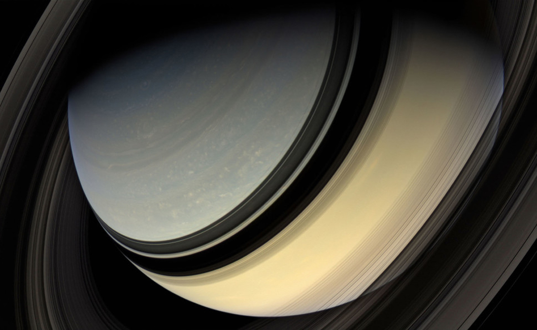 Величественная тень колец Сатурна падает на саму планету и оба ее спутника. Мимас и Тетис. Мимас — маленькая черная точка у левой вертикальной тени, Тетис расположен правее. Cassini, 16 июля 2005 года.